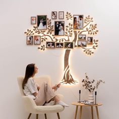 a woman sitting on a chair in front of a tree with pictures hanging from it