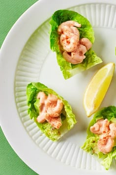 small lettuce cups filled with shrimp and lemon wedges on a white plate