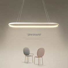 two chairs are sitting under a suspended light