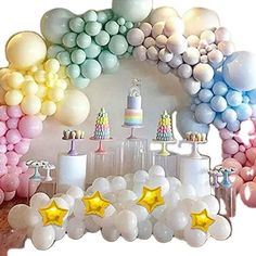 a table topped with lots of balloons and stars next to a wall filled with cake