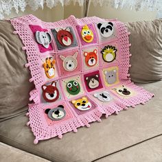 a crocheted blanket with animal faces on it sitting on a couch next to a pillow