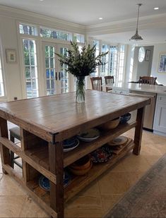 a wooden table with plates and bowls on it in a kitchen next to a window