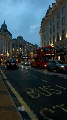 a city street filled with lots of traffic next to tall buildings at night, lit up by bright lights