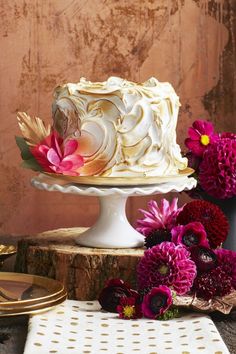 a white cake sitting on top of a wooden table next to pink and yellow flowers