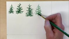 someone is drawing some trees on paper