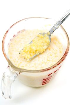 a measuring cup filled with yellow liquid and a spoon