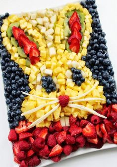 a cat made out of fruit on top of a white plate with strawberries and kiwis