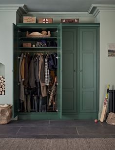 a green closet filled with lots of coats and shoes next to a wall mounted coat rack