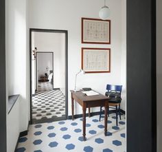 a room with white walls and blue chairs in front of a wooden table on the floor