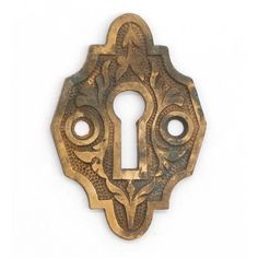 an antique brass keyhole with ornate designs on the front and back sides, set against a white background