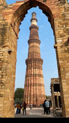 people are walking around in front of a tall tower