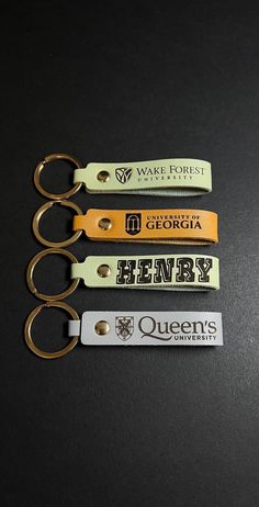 three keychains with different logos on them sitting on a black table next to each other