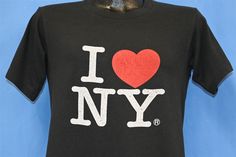 Chest 18 in.  Length 24 in.   Tag Says: No tag  This shirt features the classic "I Love New York" logo designed by Milton Glaser in the mid 70s. The graphic was later trademarked and used to promote tourism in the Big Apple.   Comments: Fits like a modern unisex adult medium, feels like cotton blend           24-10-128744 I Heart Ny, I Love New York, New York Logo, Milton Glaser, I ❤ Ny, Big Apple, Black T Shirt, Black Tshirt, Gender Neutral