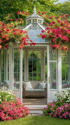 a white gazebo surrounded by flowers and greenery with a couch in the center