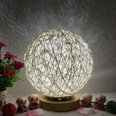 a lamp that is sitting on top of a table next to some flowers and plants