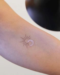 a small sun and moon tattoo on the arm