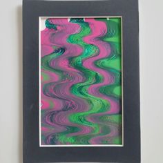 an abstract painting is framed in a black frame on the wall with a green and pink background