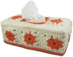 a tissue box with an orange and white crochet design on it's lid