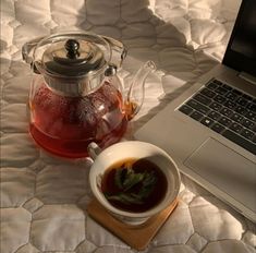 a cup of tea next to a laptop on a bed