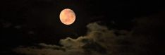 the full moon shines brightly in the night sky with clouds around it and dark skies