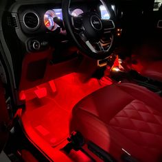 the interior of a car with red leather seats and dashboard lights, including an illuminated steering wheel