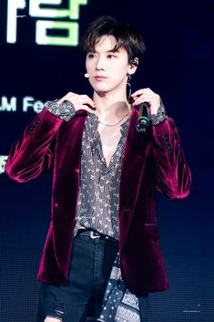 a young man in a red velvet jacket and black shorts is holding his hand up to his ear