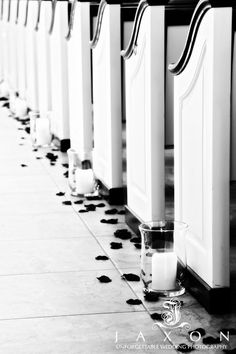 candles are lined up on the floor in front of white urinals with black and white designs