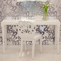 a white table and chair in front of a wallpapered room with flowers on it