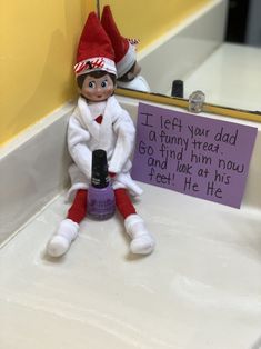 an elf is sitting on the counter next to a sign