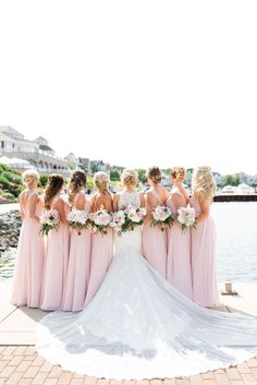 the bride and her bridesmaids are standing together by the water