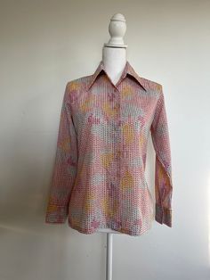 Super cool print on this lightweight, lightly textured, polyester crepe vintage Kmart button down. Longer pointed collar with a standard front button closure, with long sleeves and buttoned cuffs. The real standout feature is the awesome pattern. Tiny slightly trapezoid dots cover the entire piece, undulating in shades of pink, yellow and grey blue. Each 'dot' has a speck of green and spatter of red and a hint of taupe.  All set off with cute pink buttons. Excellent condition, no noted flaws. Kmart, 100% polyester, vintage size 34.  Measurements:  Shoulder seam to shoulder seam: 15 inches Length: 24 inches Sleeve length: 21.5 inches along outer edge Bust: 39 inches  Waist: 39 inches Pink Retro Blouse For Fall, Patterned Blouse With Button Closure For Work, Patterned Retro Print Shirt For Spring, Retro Fitted Printed Shirt, Fitted Retro Printed Shirt, Vintage Style Multicolor Blouse For Daywear, Spring Patterned Shirt With Retro Print, Retro Spring Blouse With Buttons, Polka Dot Shirt With Buttons For Spring