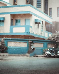 a motorcycle parked in front of a blue and white building on the side of a street