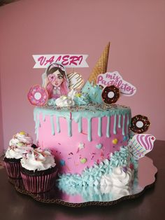 there is a pink and blue cake with frosting on the top that has an ice cream cone