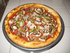 a pizza sitting on top of a pan covered in cheese and toppings next to a white tile floor