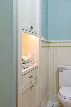 a white toilet sitting inside of a bathroom next to a sink and cabinet in a room