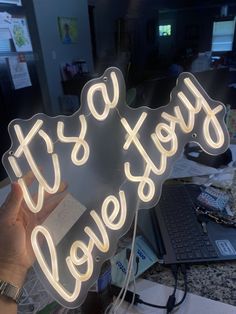 a neon sign that says it's okay to love on top of a desk