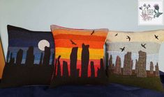 three decorative pillows on a bed with city skylines and birds in the night sky