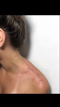 a woman with a tattoo on her neck and behind her ear is looking at the camera