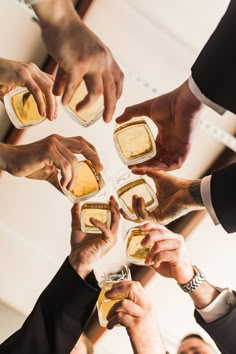 a group of people standing around each other toasting with beers in front of them