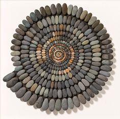 a circular design made out of rocks on a white wall