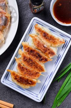 some food is sitting on a plate with chopsticks next to it and sauce