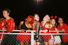 a group of people dressed in red and black posing for a photo behind a fence