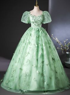 Elegantly designed to embody the beauty of nature, this mint-green Quinceanera dress is the epitome of fairytale elegance! The gown is adorned with detailed butterfly appliques, symbolizing transformation and new beginnings, which are perfectly suited for a young woman entering a new chapter in her life. The soft puff sleeves add a delicate, graceful touch, making the overall look romantic yet youthful. The voluminous skirt flows effortlessly, providing both movement and comfort as it glides across the floor. The subtle shimmer of the fabric catches the light with every step, enhancing the overall magical aura of the dress. This gown is perfect for the Quinceanera who wants to feel both regal and playful on her special day. Whether paired with a crown of flowers or sparkling jewels, this d Puffy Green Dress, Prom Dress Short Lace, Long Party Gowns, Green Evening Gowns, Champagne Prom Dress, Grey Prom Dress, Green Formal Dresses, Butterfly Lace, Mermaid Prom Dresses Lace