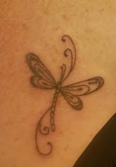 a dragonfly tattoo on the back of a woman's neck