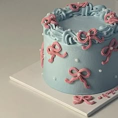 a blue and pink cake with bows on it