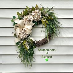 a wreath with white flowers and greenery hanging on the side of a house that says southern nn blessing