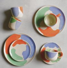 four plates with cups and saucers painted in different colors