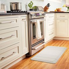 a clean kitchen with white cabinets and wood flooring is seen in this image from the front view