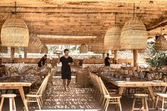 a man standing in the middle of an outdoor dining area with tables and stools