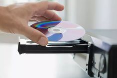 a hand is holding a cd in front of a computer screen with the disc on it